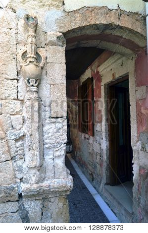 Old portico in stones with a sculture on the right.