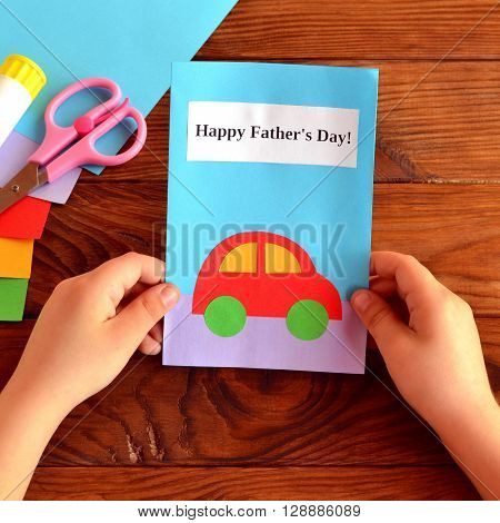 Child holds a card in his hands. Greeting card Happy father's day. Paper sheets, scissors, glue. How to make a greeting card father's day