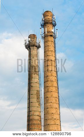 Defunct industrial brick chimney against bright blue sky