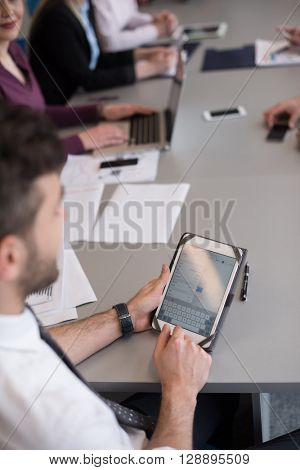 close up of  businessman hands  using tablet, people group in office meeting  room blurred in backgronud