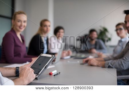 close up of  businessman hands  using tablet, people group in office meeting  room blurred in backgronud