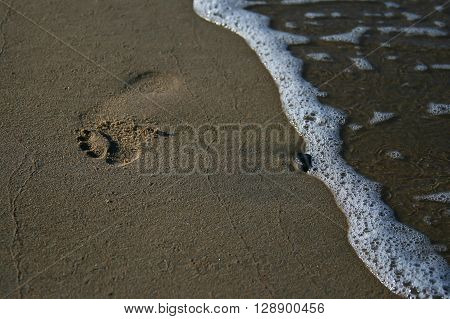 wave and footmark on the seaside at sunset