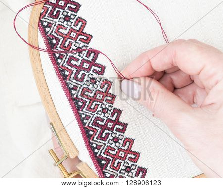 Fragment of embroidery on linen and hands of the master