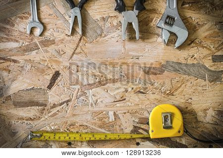 The working tools for construction and repair of house: tape measure (yardstick), wrench, pliers, spanner. Photo with copy space and vignetting effect.