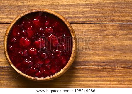 German Rote Gruetze (red groats) red berry pudding made of strawberry blueberry raspberry and redcurrants cooked with sugar and starch photographed overhead on wood with natural light