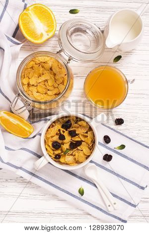 Breakfast concept with corn flakes, milk, dry cranberry and orange juice. Top view