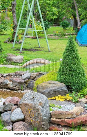 Alpine garden with bridge and small pond with water