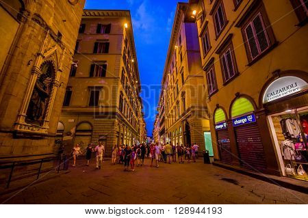 FLORENCE, ITALY - JUNE 12, 2015: Florence at night. Shops open late on summer, people visiting historical center, nice buildings with holding blue sky.