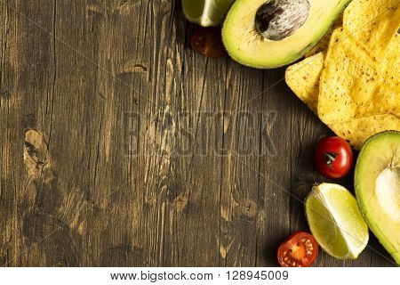 Corn tortilla chips Nachos and Guacamole sauce ingredients on wooden table. Top view