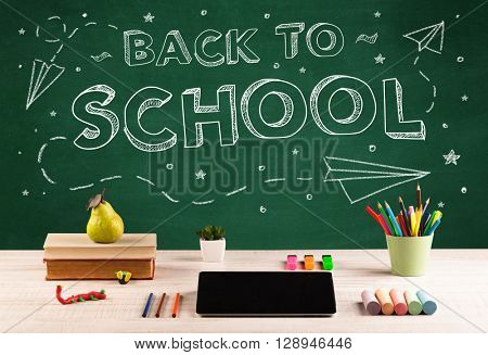 Back to school concepty with writing on blackboard and desk, apple, books, items