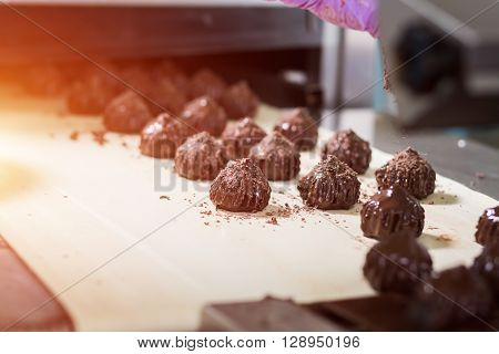 Brown sweets on beige cloth. Dark candies with shavings. Dream of a gourmet. Special recipe of savoury dessert.