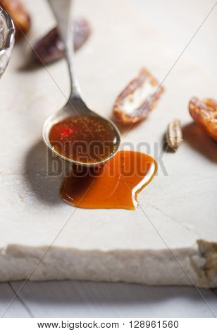 Close up of spoonful of sweet date syrup and few dates.