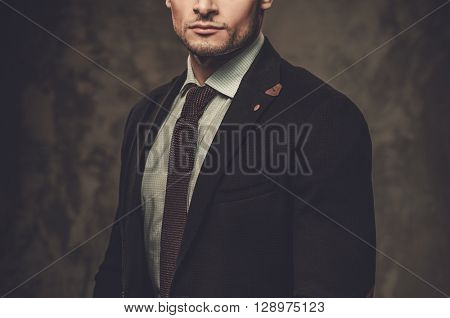 Serious well-dressed hispanic man posing on dark background. 