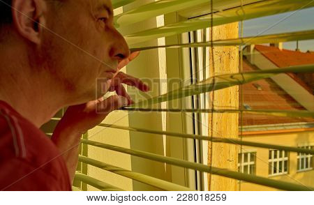 Midlle Age Man Looking Through A Jalousie. Themes Curiousity, Surveillance Or Eyesight.