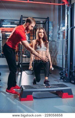 Personal Trainer Helps The Girl To Do Exercises In The Gym