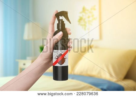 Woman holding bottle of anti bed bug detergent in bedroom