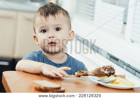 Child In The Kitchen Eating Mashed Potatoes, Spoon, Next To The Plate Is A Piece Of Chicken Meat