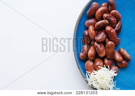 Red Canned Beans With Fresh Horse-radish In Blue Ceramic Plate Over White Background, Copy Space