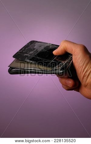 Broken Black Mobile Smartphone With A Cracked Display Lying In His Hand, On A Lilac Background, A Ve