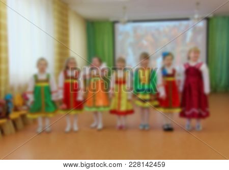 Folk Dances Of Children Theme Abstract Blur Background With Bokeh Effect. Children In Bright Folk Co