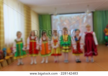 Folk Dances Of Children Theme Abstract Blur Background With Bokeh Effect. Children In Bright Folk Co