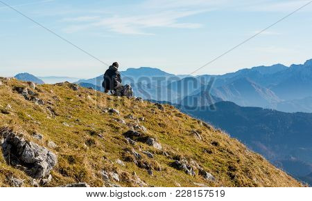Lonely Hiker Sitting And Looking Into Distant Mountains. Meditations In Nature.