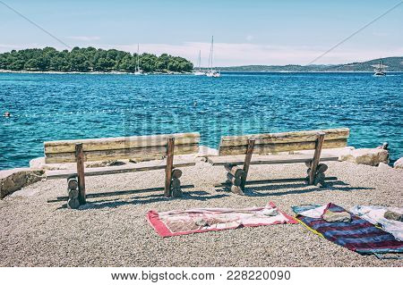 Wooden Benches And Towels On The Beach, Solta, Croatia. Summer Vacation. Sea With Yachts Scene. Blue
