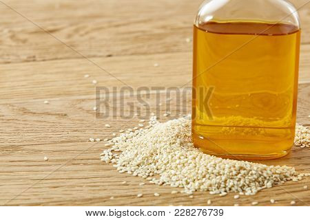 Peeled Sesame Seeds With Oil In A Small Transparent Glass Bottle Over Rustic Wooden Background, Shal