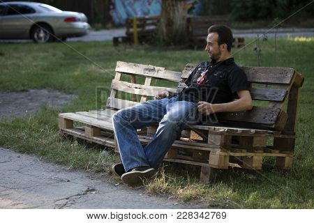 Man And A City. The Tramp Is Siting On The Old Pallets.