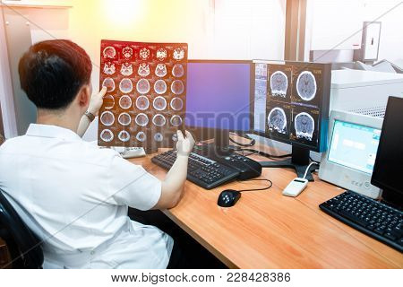 Doctor Working With Ct Scan Monitor And Computer In Radiology Room.