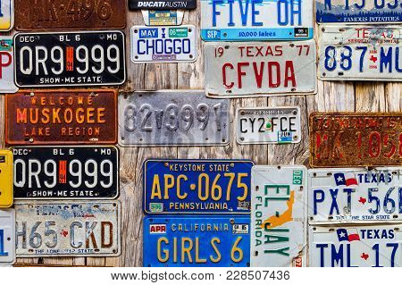 Luckenbach, Tx - January 11, 2018 - Various Old License Plates Displayed On A Wooden Wall.