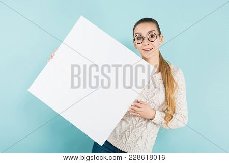 Portrait Of Attractive Happy Woman In Sweater And Round Glasses Isolated On Blue Background Holding 