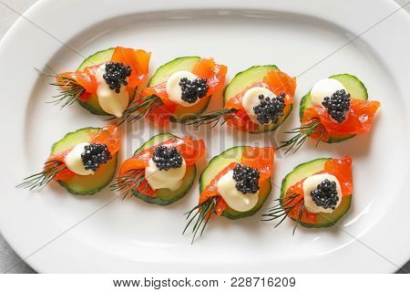 Delicious canapes with black caviar on plate