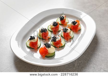 Delicious canapes with black caviar on plate