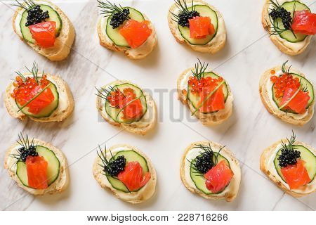 Delicious canapes with black and red caviar on light background