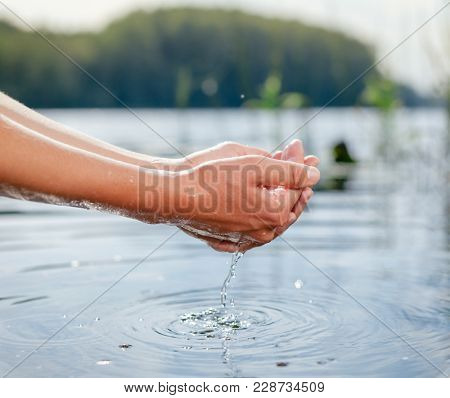 Woman taking raw unfiltered water from a natural source by cupped hands
