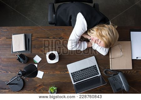 Overhead View Of Businesswoman Sleeping At Table In Office