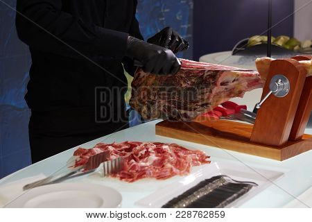 Sliced Dried Chamon Prosciutto. A Man Cuts A Jamon, A Warm Toned Image. Selective Focus Point