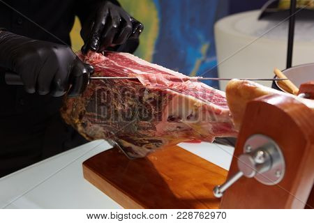 Sliced Dried Chamon Prosciutto. A Man Cuts A Jamon, A Warm Toned Image. Selective Focus Point
