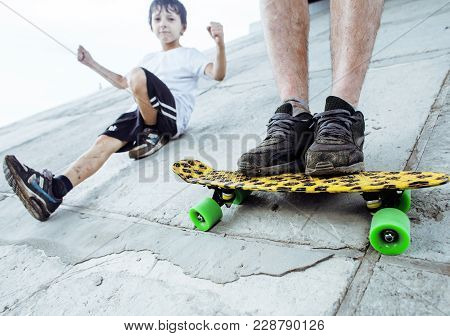 Little Cute Boy With Skateboard On Playground Training With Father, Making Funy Faces Close Up, Life