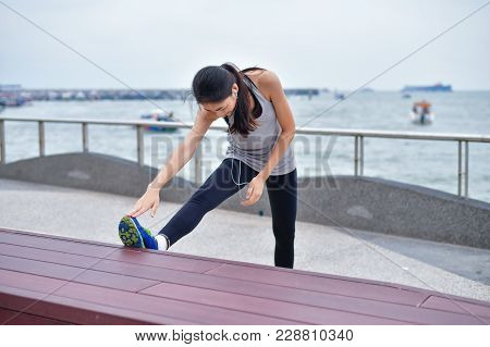Sports Concept. Beautiful Girl Is Exercising On The Beach With Warm Up. Beautiful Girl Is Happy To E