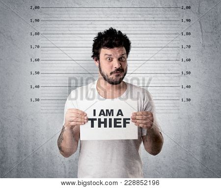 Caugth offender in front of a wall with table in his hand.