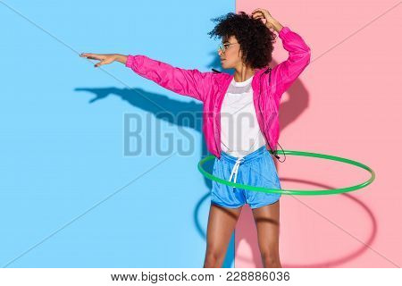 Sporty Woman Posing While Exersizing With Hoop On Pink And Blue Background