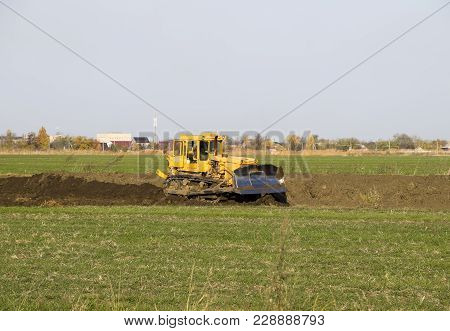 The Yellow Tractor With Attached Grederom Makes Ground Leveling. Work On The Drainage System In The 