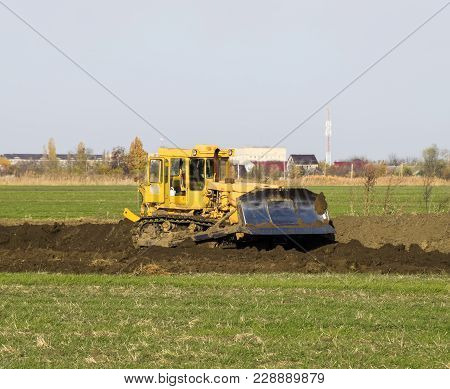The Yellow Tractor With Attached Grederom Makes Ground Leveling. Work On The Drainage System In The 
