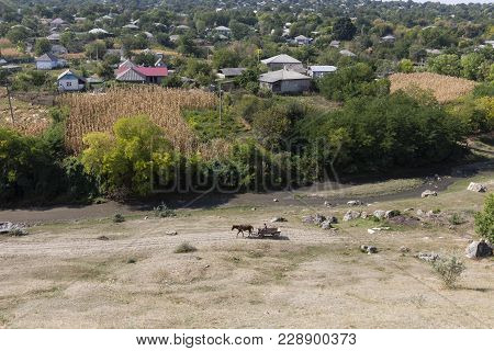 View On The Village. River Near A Village And Stonefield.