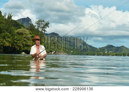 Elderly Man Fishing In The Sea With A Fishing Rod