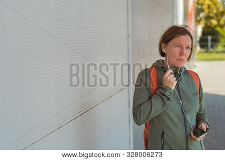 Female Jogger Talking On Mobile Phone Handsfree While Brisk Walking The Street