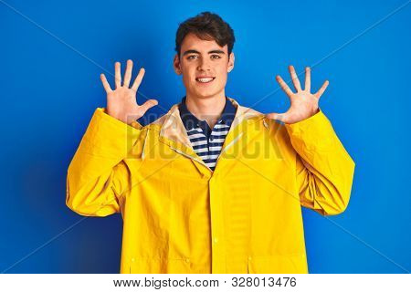 Teenager fisherman boy wearing yellow raincoat over isolated background showing and pointing up with fingers number ten while smiling confident and happy.