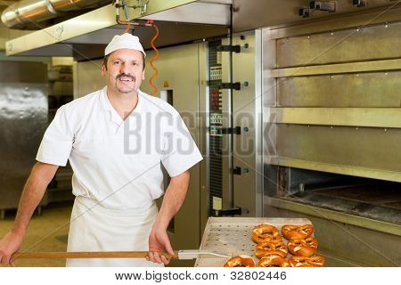 padeiro em pé na sua padaria na parte da manhã e assa pão ou pãezinhos
